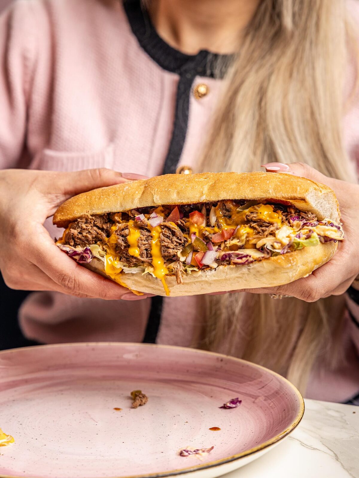 A long roll packed with pulled beef, melted cheese, slaw and sauce